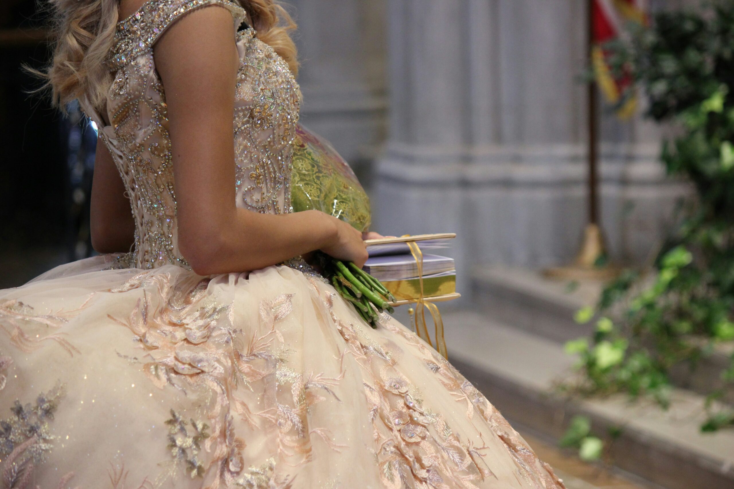 partial view of a woman holding a bouquet while wearing a ball gown