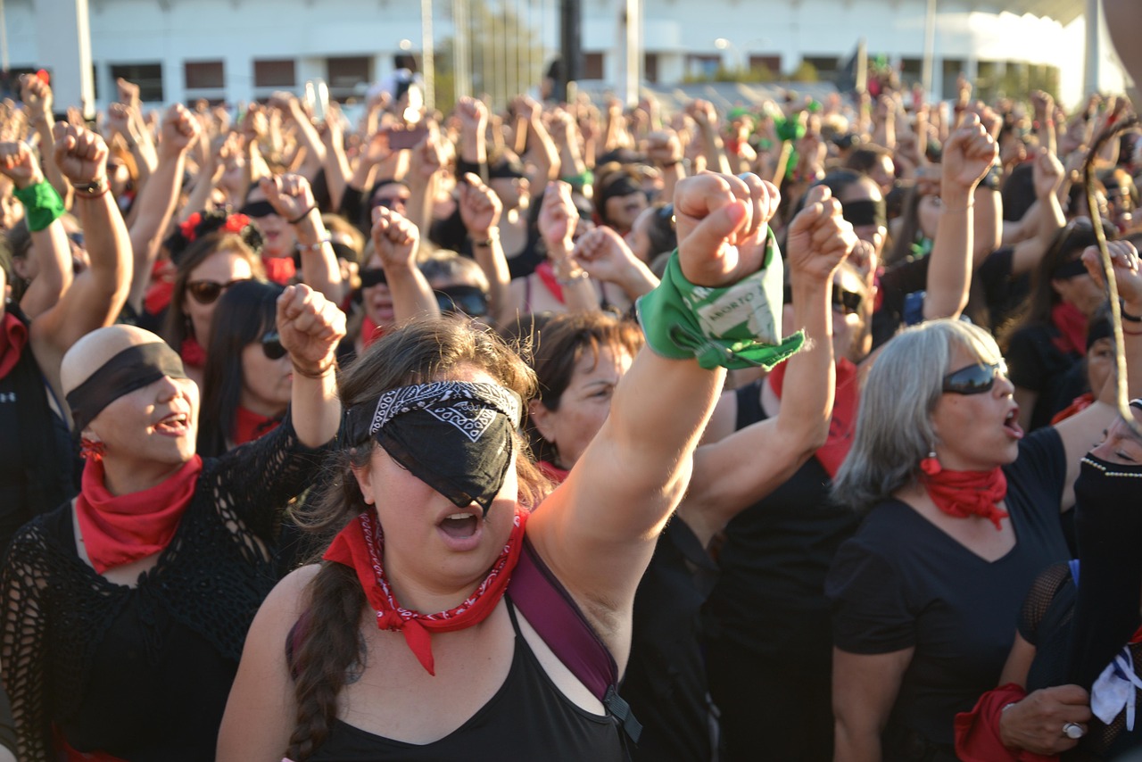 women marching with green scarves on their wrists and bodies