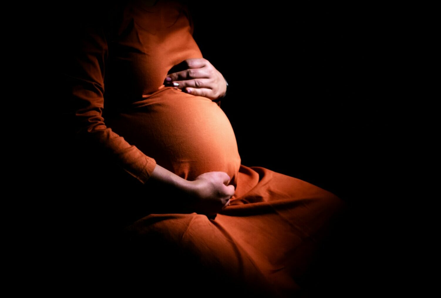 partial view of a pregnant woman in orange dress